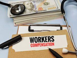 Concept of workers' compensation written on paperwork with money and gavel